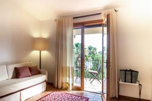 a living room with a couch and a sliding glass door at Hotel Aquadulci in Chia +37 photos