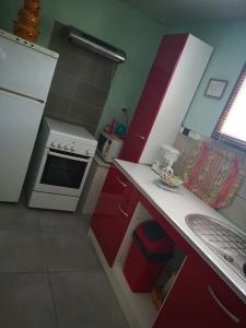 a kitchen with red cabinets and a white stove at P'tite Case in Mornas