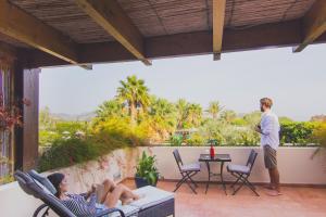 a man standing on a patio with two women laying on chairs at Hotel Aquadulci in Chia