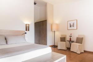 a white bedroom with a bed and two chairs at Hotel Aquadulci in Chia