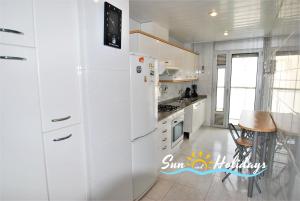 クベリャスにあるApartamento Cubellesの白いキッチン(冷蔵庫、テーブル付)