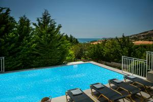 a swimming pool with chairs and the ocean in the background at Sea View Villas in Skala Kefalonias
