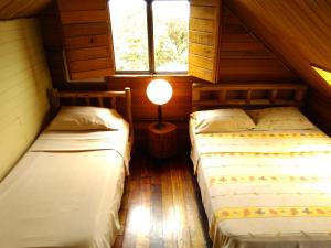 two beds in a room with a lamp on a table at Iyok Ami (Madre Tierra) in Cartago