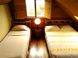 2 camas en una habitación con una lámpara en una mesa en Iyok Ami (Madre Tierra), en Cartago