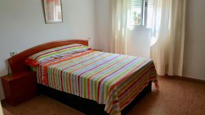 sypialnia z łóżkiem z kolorowym kocem w paski w obiekcie Apartamento Roquetas playa con WIFI w mieście Roquetas de Mar
