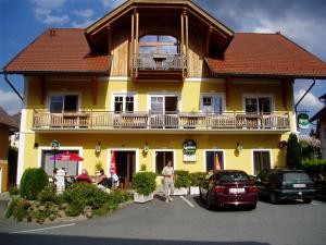um edifício amarelo com uma varanda em cima em Gasthaus zum Fuchs - Familie Andrä em Hermagor