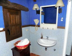 Un baño azul con lavabo y espejo. en Casas Rurales Lagunas de Ruidera - Piscina, en Ossa de Montiel