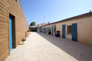 an alley between two buildings with blue doors and potted plants at NAT-SEB 13 Avenue de Beaulieu in Marennes