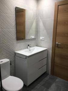 a bathroom with a sink and a toilet and a mirror at Casón del Comercio in Toledo