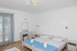 a white bedroom with a bed and a mirror at Golden Bay in Agios Prokopios