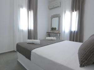 a white bedroom with a large bed and a mirror at Bonatsa House in Agios Georgios