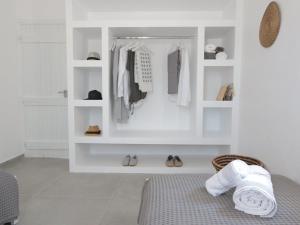 a bedroom with white shelves and a bed with towels at Bonatsa House in Agios Georgios