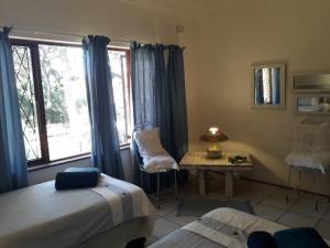 a bedroom with two beds and a table and a window at Milkwood Beach Cottages in Shelly Beach