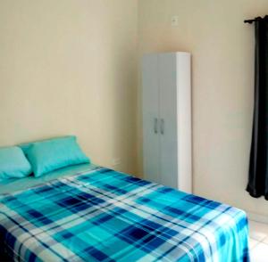 um quarto com uma cama com um cobertor xadrez azul em Pousada Oluap em Mairiporã