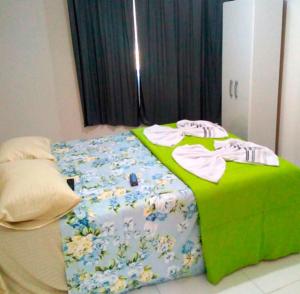 a bed in a room with a green blanket and clothes on it at Pousada Oluap in Mairiporã