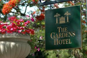 a sign for the gardens hotel with a vase with flowers at The Gardens Hotel in Key West