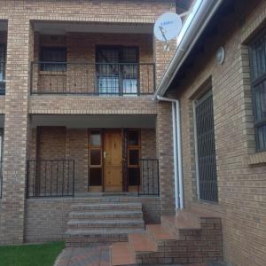 Casa de ladrillo con puerta y balcón en Vinolux Guest House en Mthatha