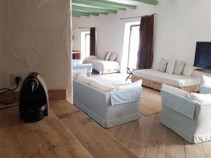 Il comprend un salon doté d'un mobilier blanc et d'une télévision. dans l'établissement Apartamento Poal-Cadaques, à Cadaqués