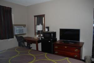 a hotel room with a bedroom with a desk and a television at Super 8 by Wyndham Warner Robins in Warner Robins