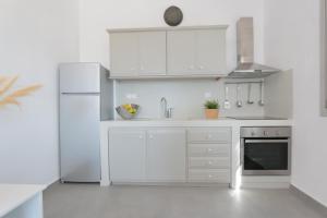 a kitchen with white cabinets and a refrigerator at Bonatsa House in Agios Georgios
