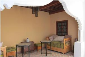 Habitación con 1 cama y 2 mesas en una habitación en Hôtel Ras El Maa, en Chefchaouen