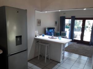a kitchen with a white counter and a refrigerator at Milkwood Beach Cottages in Shelly Beach