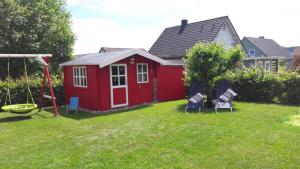 a red shed with two chairs in a yard at Ferienwohnung Rockmann in Kirchenlamitz