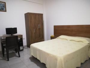 a bedroom with a bed and a desk with a television at Mi Bella Santa Cruz in Santa Cruz de la Sierra