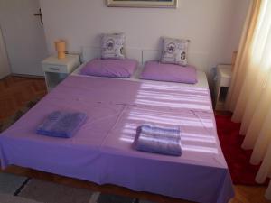 a purple bed in a room with two purple pillows at Beachfront Apartment Jelsa in Jelsa