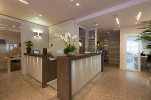 un hall de bureau avec un comptoir de réception orné de fleurs dans l'établissement Hotel Rosenblatt, à Cervia