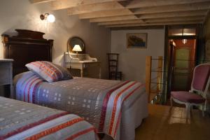 a bedroom with two beds and a table and a chair at La Voureyline in Saint-Antoine
