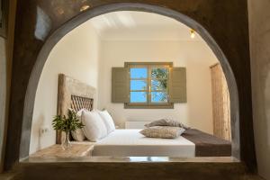 1 dormitorio con cama y ventana abovedada en Elixirium villa en Perissa