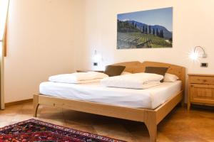 sypialnia z drewnianym łóżkiem z białą pościelą w obiekcie Agritur Casteller w Trydencie