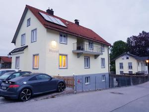 une voiture bleue garée devant une maison blanche dans l'établissement House LA Neuschwanstein Blick, à Füssen