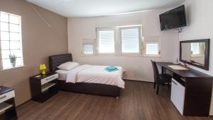 a bedroom with a bed and a desk and a television at Guesthouse Stari Grad in Mostar