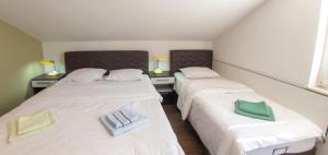 two beds in a room with white sheets and green pillows at Guesthouse Stari Grad in Mostar