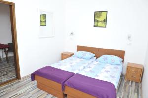 Schlafzimmer mit einem Bett mit lila Bettwäsche und Kissen in der Unterkunft Apartments Neda in Ploče