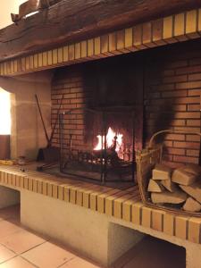 a brick fireplace with a fire in it at Gite CAP de BOUÉOU in Troncens