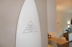 a surfboard leaning against a wall with a sign on it at The Surf Studio - Ericeira in Ericeira