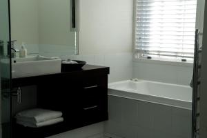 a white bathroom with a sink and a bath tub at The Dome Boutique Apartments in Napier