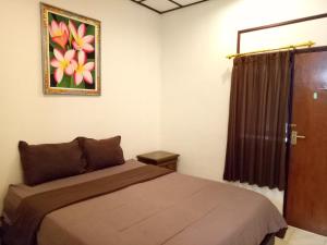 a bedroom with a bed and a picture on the wall at Wiran Homestay in Canggu