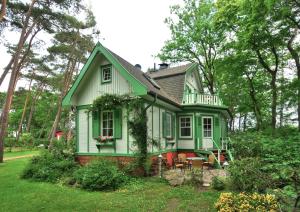 ein grünes Haus mit einem Balkon auf einem Hof in der Unterkunft Landhaus Victoria in Boltenhagen