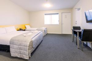 a room with two beds and a desk and a computer at C-Motel in Christchurch