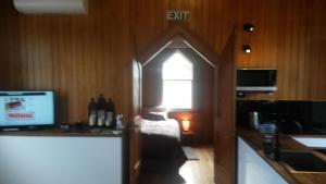 a room with a kitchen with a window and a television at St Andrews Church Nave in Ophir