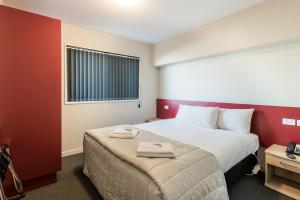 a hotel room with a bed with two towels on it at C-Motel in Christchurch
