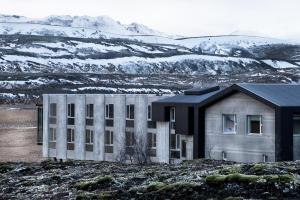 a building in a field with a snow covered hill at ION Adventure Hotel, Nesjavellir, a Member of Design Hotels in Nesjavellir