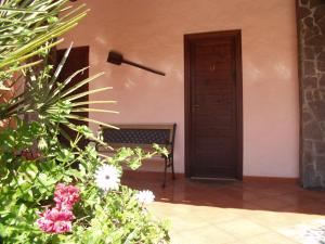 a bench in front of a door with flowers at Agriturismo la Mimosa in Putzu Idu