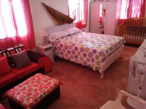 a bedroom with a bed and a red couch at Hillside Country Home in Santa Bárbara de Samaná