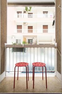 Athens spacious apartment في أثينا: اثنين من المقاعد الحمراء على شرفة مع مبنى