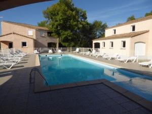 una piscina con sillas blancas y un edificio en les vignes, en Lablachère